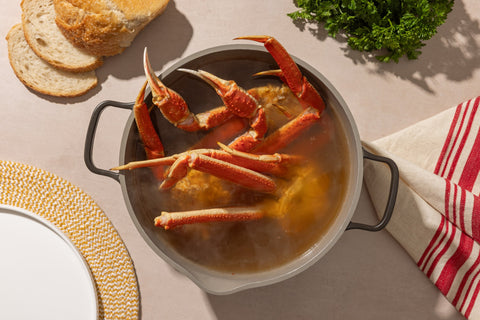 Snow crab clusters reheating in a pot with corn and seasoning