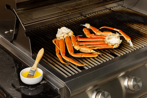Snow crab clusters on a grill beside melted butter