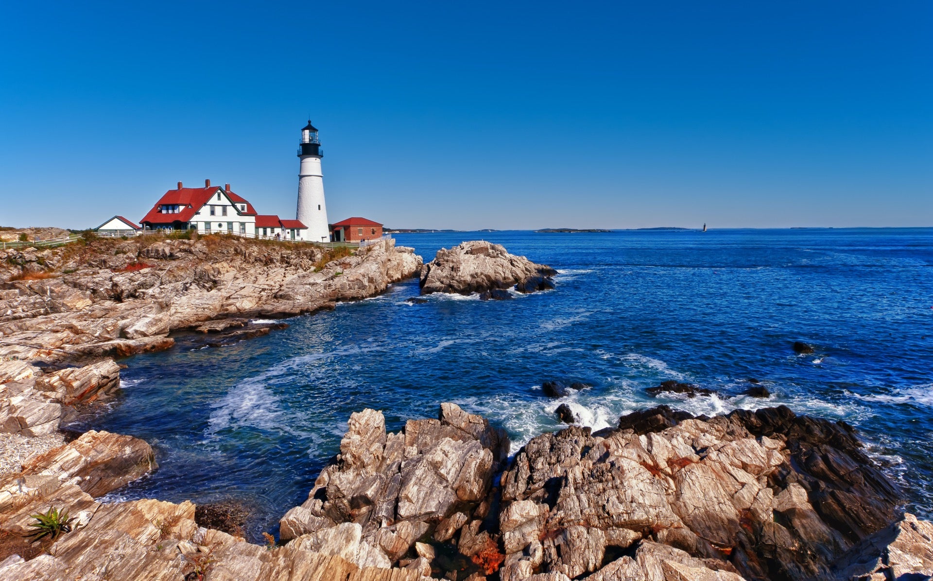 White lighthouse with red roof along the water